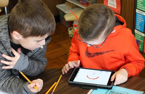 Two boys working on math using tablets.