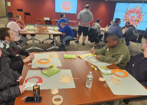 Groups of people at tables making turkey crafts for Thanksgiving