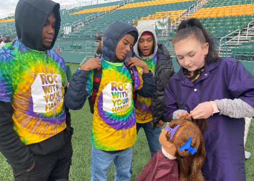 Female student demonstrates hairstyling as three additional students watch