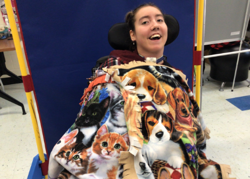 Student displaying handmade blankets featuring images of dogs and cats