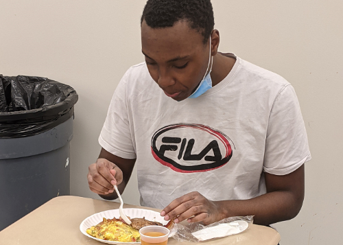 Student in white tshirt eating breakfast