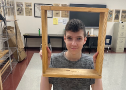 Student holding wooden frame