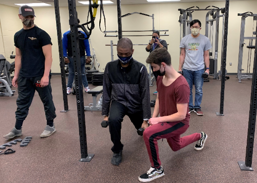 Food Services student Brandon Williams (left center) learns about proper form using free weights with Exercise Science student Garrett Spychala. Looking on are students Jake Affronti at left and Paul Pham.