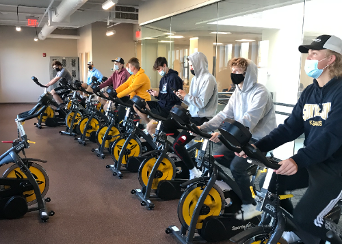 Students on a row of exercise bicycles that generate electricity