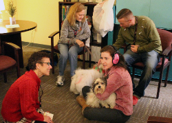 Student holding therapy dog with several staff members