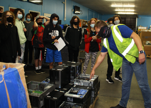 Computer Technology students look at a pallet of desktop computers