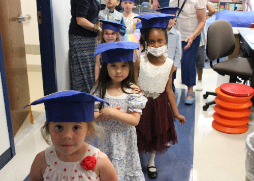 Preschoolers wearing graduation caps