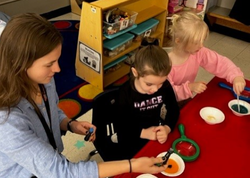 Teacher with two students making colored liquids