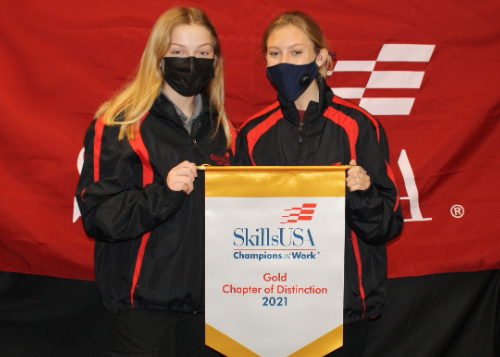 Two students standing behind award banner