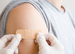 hands applying bandaid to someone's arm