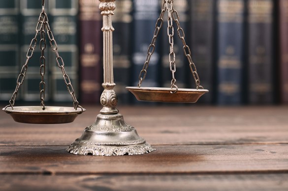 Scales of Justice and Law books on a wooden background. 