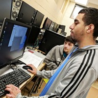 Two career and technical education students view a computer screen together while one of them uses the computer keyboard and mouse.